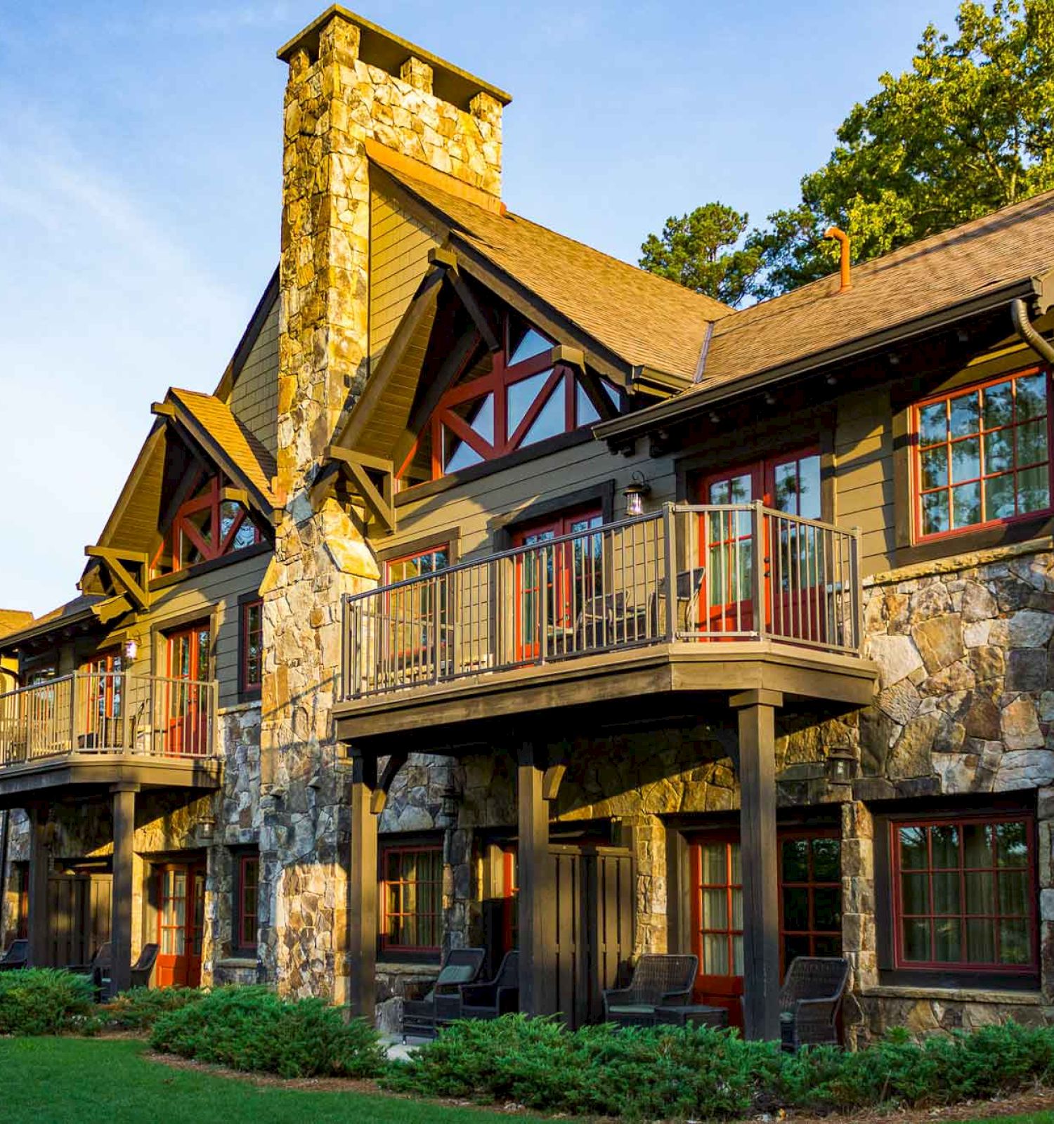 A large house with stone foundation, wooden beams, balconies, and greenery.