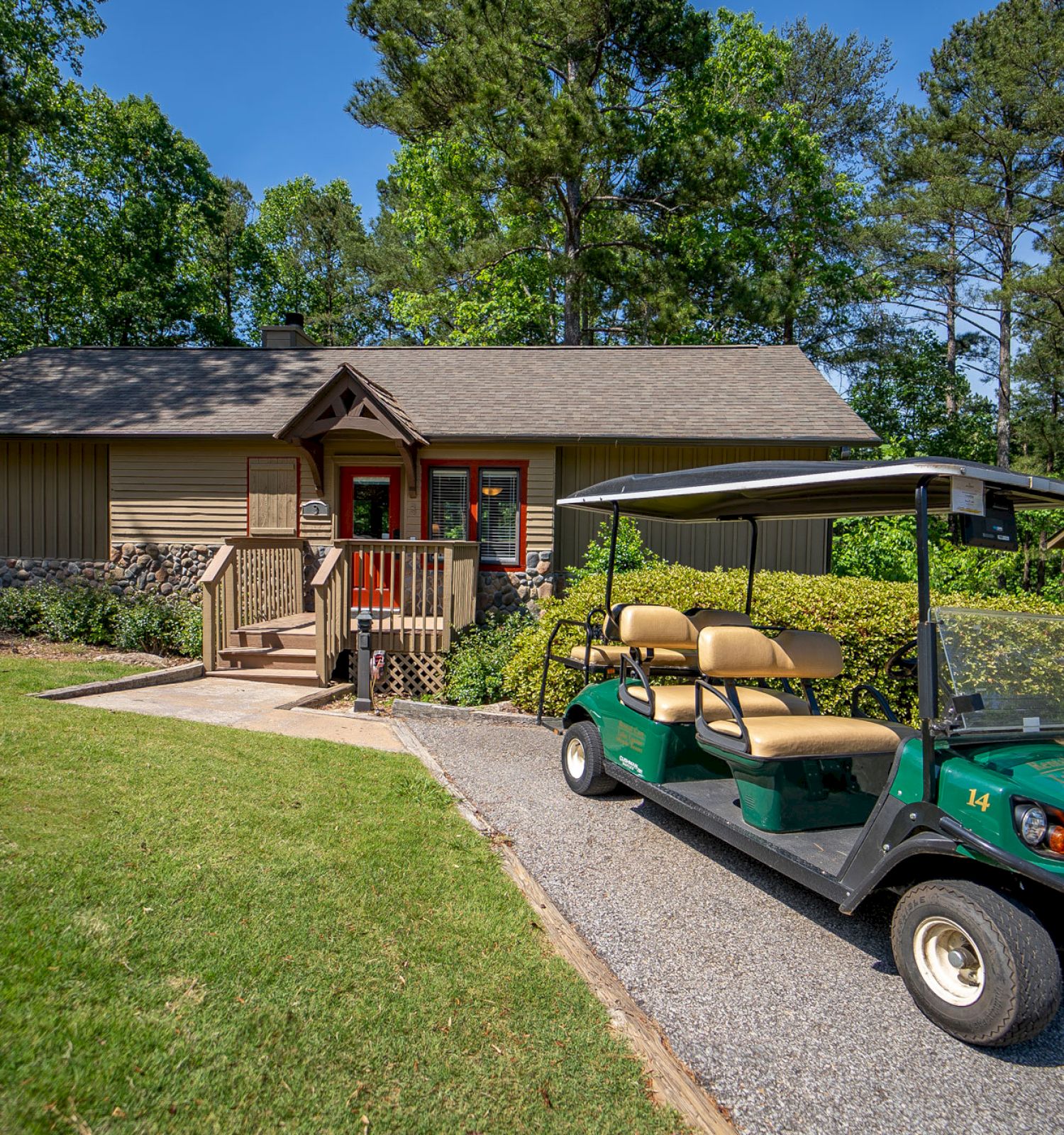 A golf cart parked in front of a house with trees in the background.